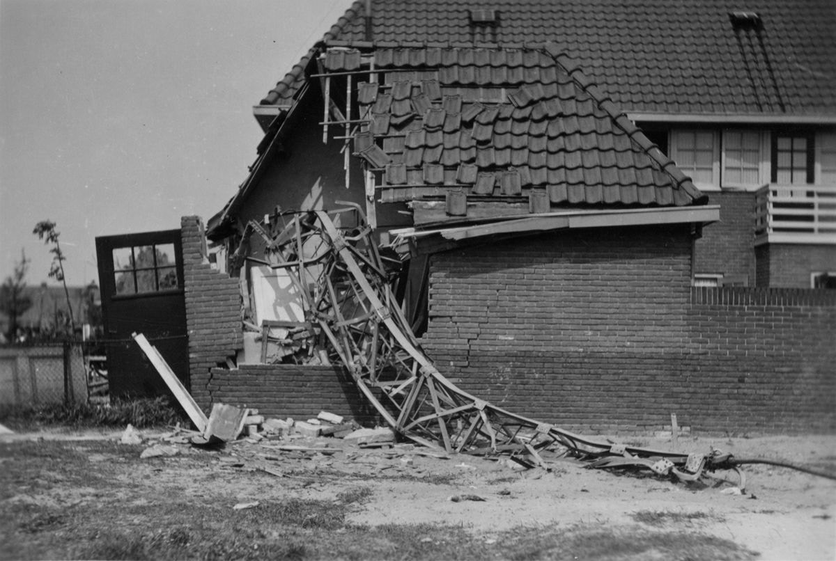 De gevallen stalen zendmast van de NSF op een woning in de Meteorenstraat, mei 1940. De constructie heeft het dak en de gevel doorboord.